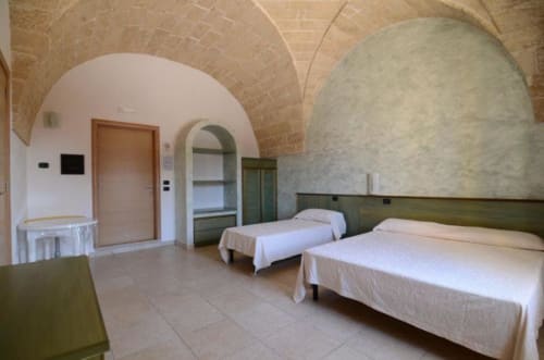Camera tripla a B&B Villa Arneide a Torre Lapillo con soffitti a volta, tre letti e architettura in laterizio terracotta