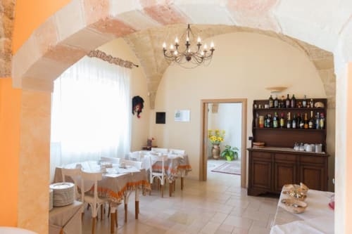 Elegante sala da pranzo del B&B Villa Arneide a Torre Lapillo con soffitti a volta, mobili in legno e scaffali per vini.