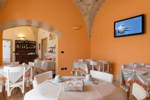 Camera quadrupla di B&B Villa Arneide a Torre Lapillo con pareti arancioni, tavoli rotondi e soffitti a volta