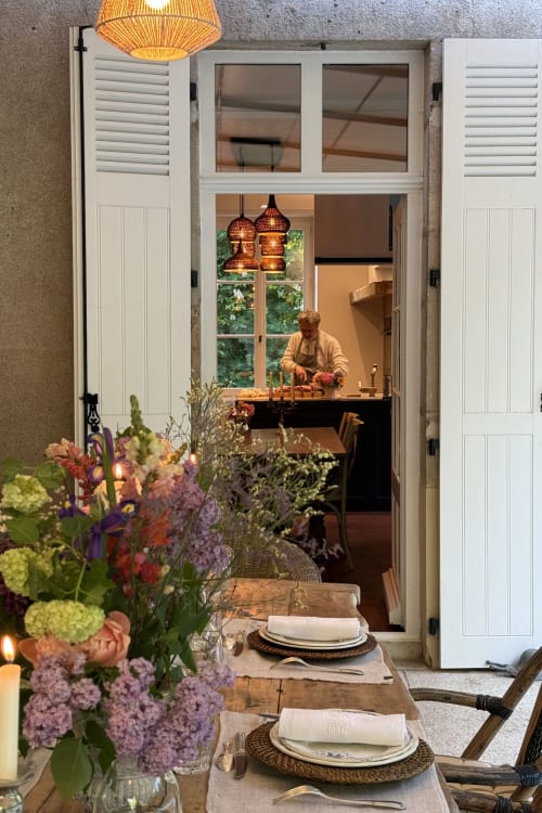 La Maison 1680 dining room with set table, flowers, and chef working at counter in Couches