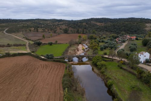 Aerial view of Moinho do Maneio B&B in Penamacor, Portugal with river, bridge, and rolling countryside