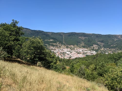 Panoramic view of Penamacor village nestled in forested mountains, visible from Moinho do Maneio in Portugal
