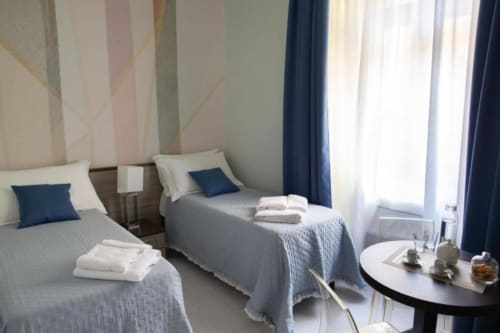 Camera doppia all'Exclusive Domus Gaudia hotel di Roma con due letti, cuscini blu e arredamento moderno