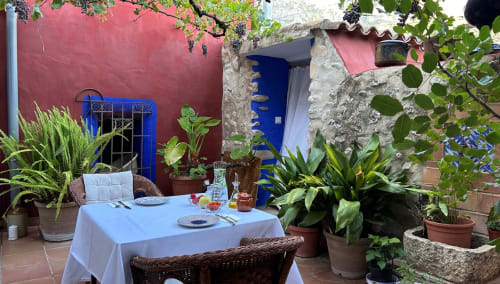 Charming courtyard dining setup at Casa Gallinera in Benissivà with colorful walls, potted plants, and mountain views