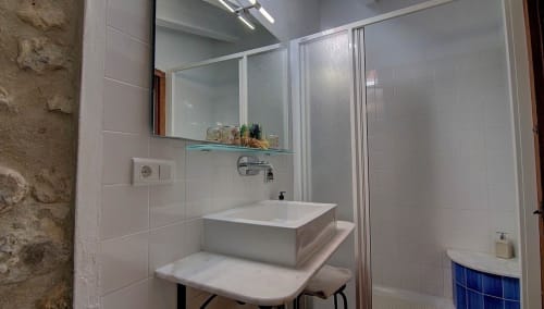 Modern bathroom in Els Llombos room at Casa Gallinera, Benissivà, featuring white basin sink, shower enclosure, and mirror