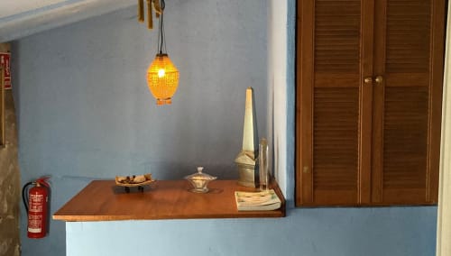Casa Gallinera room detail with wooden shelf, hanging pendant lamp, decorative items and wooden cabinet doors in El Colomer