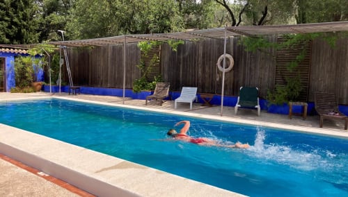 Swimmer doing freestyle in turquoise pool at Casa Gallinera, Benissivà, with wooden deck and loungers