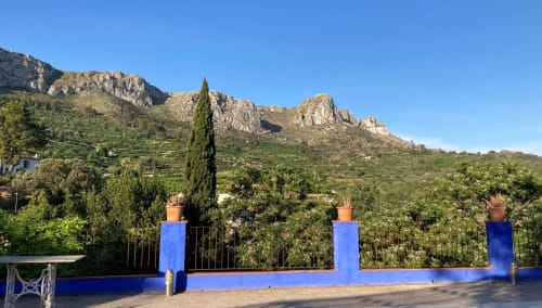 Blue terrace at Casa Gallinera with mountain views, potted plants, and Mediterranean landscape in Benissivà