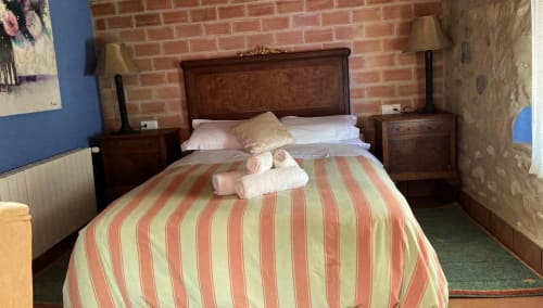 L'Umbria room at Casa Gallinera in Benissivà with striped bedding, wooden furniture, and exposed brick wall
