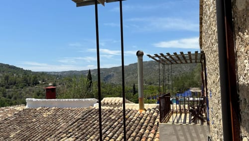 Casa Gallinera balcony overlooking terracotta roofs and mountains in Benissivà, Spain