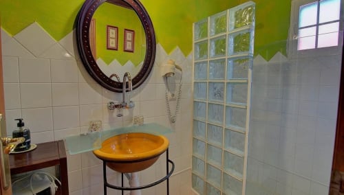 Bright bathroom in Casa Gallinera room with yellow bowl sink, decorative mirror, and glass block window