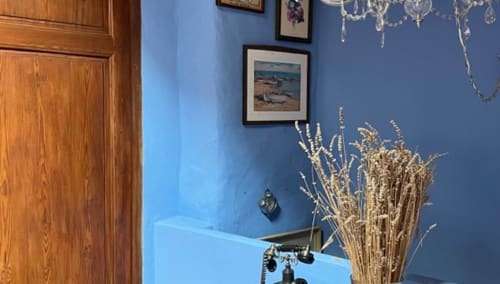 La Solana room at Casa Gallinera in Benissivà with blue walls, wooden door, framed artwork, dried flowers, and vintage