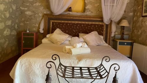 Elegant bedroom at Casa Gallinera's La Solana room with canopy bed, cream linens, and period décor in Benissivà