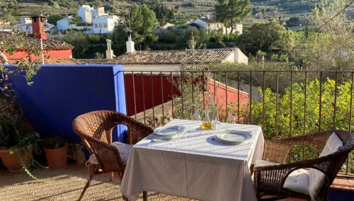 Outdoor dining area at Casa Gallinera in Benissivà with mountain views, wicker chairs, and set table