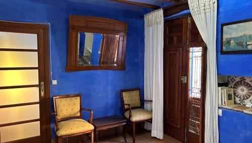 Bright blue room at Casa Gallinera with wooden doors, yellow chairs, and mountain view in Benissivà, Spain