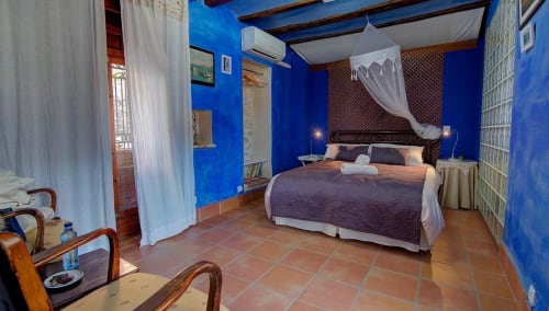 Llimaner room at Casa Gallinera in Benissivà with vibrant blue walls, terracotta flooring, and mountain views from canopied