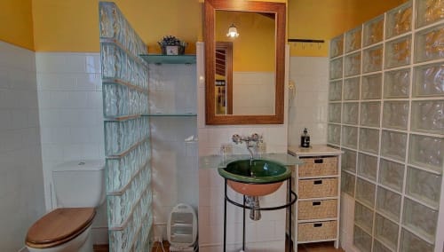 L'Albureca bathroom at Casa Gallinera, Benissivà with green basin sink, glass block shower, and wooden cabinet storage