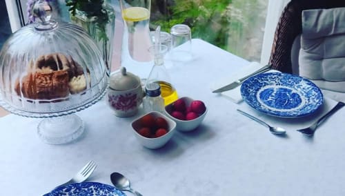 Elegant dining setup at Casa Gallinera with blue patterned plates, fresh fruit bowls, and baked goods under glass dome on