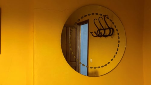 Circular mirror with decorative dashed frame on bright yellow wall in Casa Gallinera room