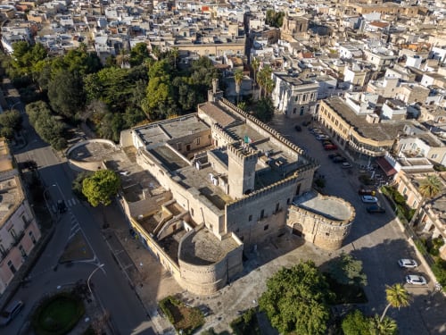Vista aerea dell'hotel Torre Lapillo, storica fortezza in pietra circondata da edifici della città mediterranea e aree verdi