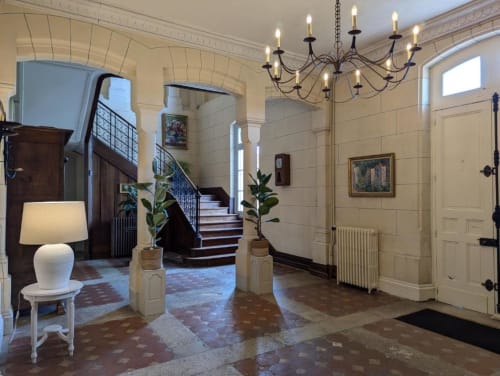 Hall d'entrée élégant du Domaine du Faure avec lustre, escalier et décor français classique