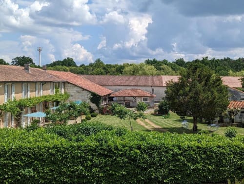 Cour du gîte Domaine du Faure avec bâtisses en pierre, toits en terre cuite, jardins verdoyants et vues champêtres à Chadurie
