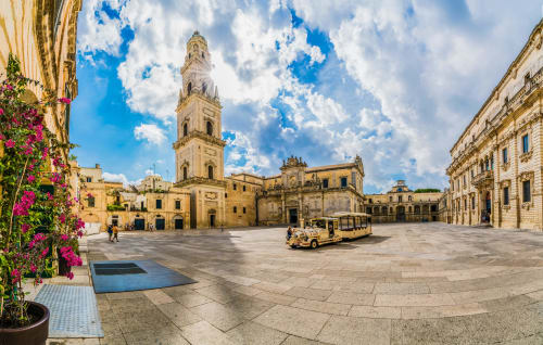 Piazza storica italiana con architettura barocca, campanile e fiori colorati vicino a Torre Lapillo