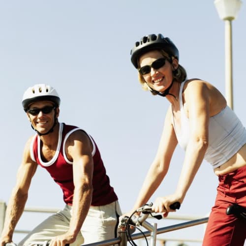 Deux cyclistes souriants avec casques de sécurité et lunettes de soleil par beau temps près du Domaine Pont Juillet à Fontaines