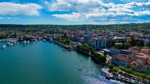 Vista aerea degli Apartments MiSaNi in Italia con fronte mare turchese, imbarcazioni e skyline cittadino