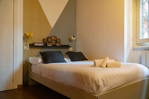 Camera moderna dell'hotel A-waay a Torino con letto queen size, testiera scura, arte geometrica gialla e luce naturale da