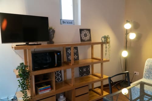 Moderna zona living torinese con scaffalatura in legno, TV, oggetti decorativi e lampada a sospensione globo