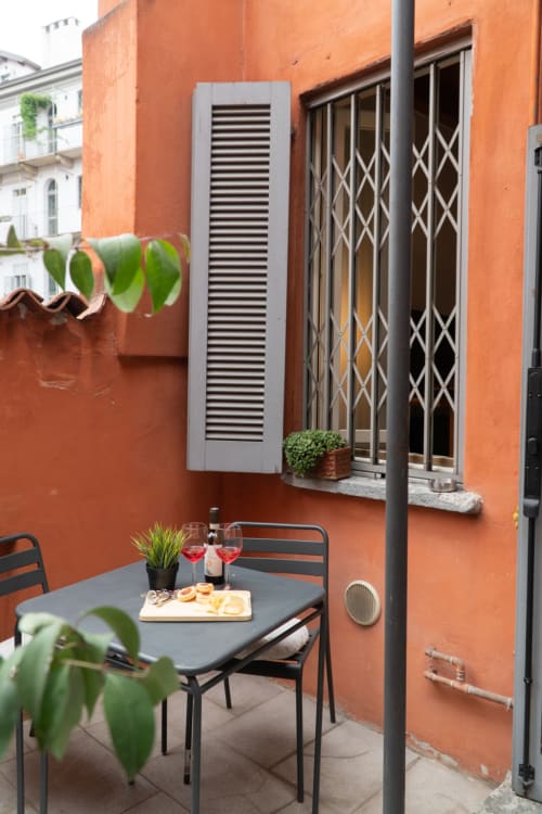Terrazza Naviglio Grande Suite a Torino con tavolo da pranzo, bicchieri di vino e stuzzichini su muro in laterizio