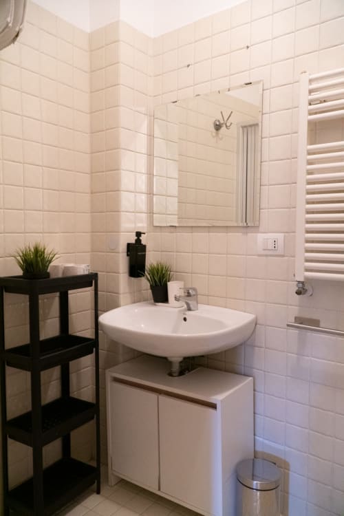 Bagno moderno nella Naviglio Grande Suite dell'A-waay Turin con piastrelle bianche, lavabo rotondo, specchio e mensole nere