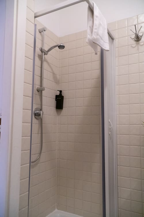 Moderna cabina doccia con pareti in piastrelle beige e soffione pioggia nella Naviglio Grande Suite dell'hotel A-waay, Torino