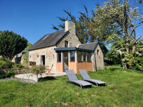 Le cottage La Boulangerie au Clos Des Sources avec transats, façade en pierre et jardins aménagés à Isigny-sur-Mer.