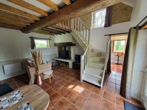 Séjour de la Boulangerie au Clos Des Sources : poutres apparentes, cheminée et escalier vers chambre en mezzanine
