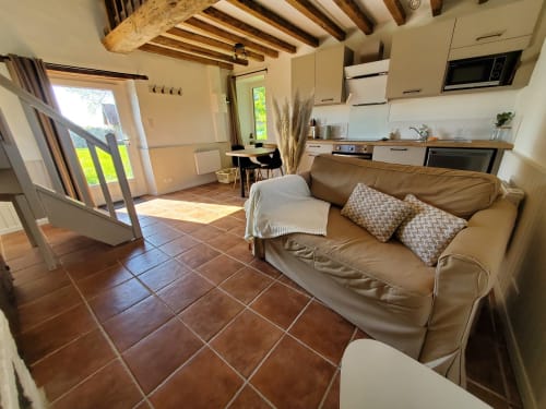 Séjour lumineux ouvert du gîte La Boulangerie au Clos Des Sources, Isigny-sur-Mer, avec canapé beige et cuisine