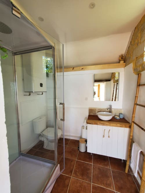 Salle de bain contemporaine du gîte La Boulangerie à Isigny-sur-Mer avec douche, vasque blanche et touches de bois
