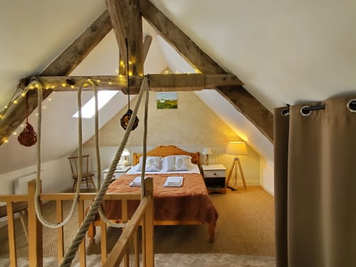Chambre rustique du Clos Des Sources avec poutres apparentes, balançoire corde et vue sur le jardin à Isigny-sur-Mer