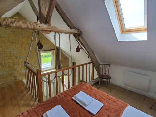Chambre mansardée de la Maison La Boulangerie au Clos Des Sources, Isigny-sur-Mer, avec poutres apparentes, lucarne et vue sur le jardin