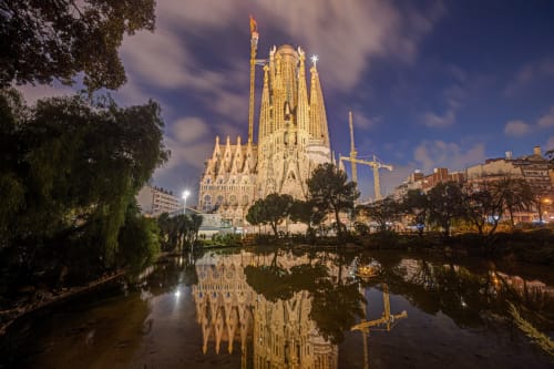 Basílica de la Sagrada Familia iluminada al atardecer, reflejada en el agua, Barcelona España