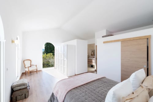 Spacious master bedroom in luxury Cannes villa with pool view, featuring wood sliding doors and elegant furnishings