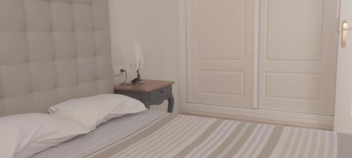 Moderno dormitorio en apartamento La Palma de Smart Rent Fuerteventura con cama, cabecero tapizado, mesita de noche y armario