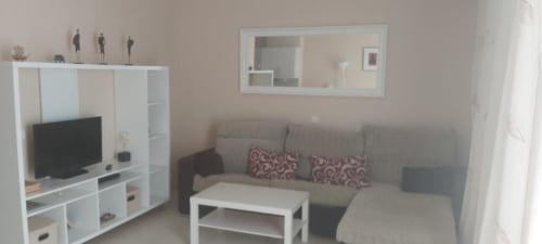 Sala moderna en apartamento de La Palma en Smart Rent Fuerteventura con sofá gris, mueble TV blanco y televisor de pantalla plana