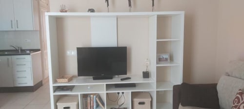 Sala de estar con estantería blanca, televisor de pantalla plana y sofá en apartamento de La Palma, Smart Rent Fuerteventura