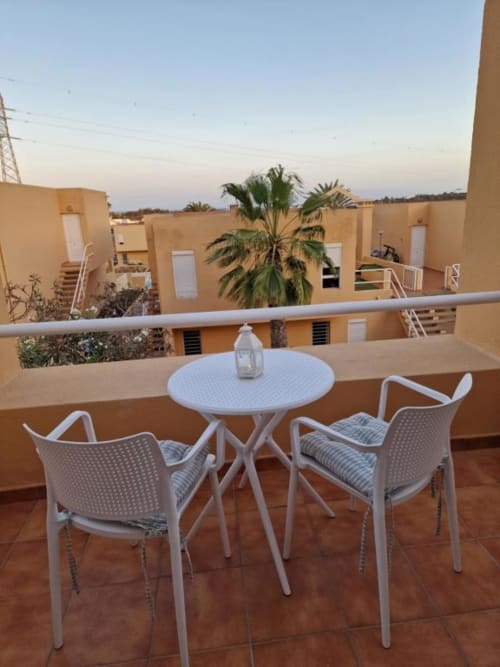 Terraza en azotea de Smart Rent Fuerteventura con mesita blanca, sillas y palmera con vistas al complejo residencial