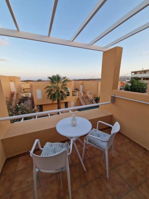 Terraza con pérgola, sillas y mesa blancas en Smart Rent Fuerteventura, con vistas al paisaje desértico