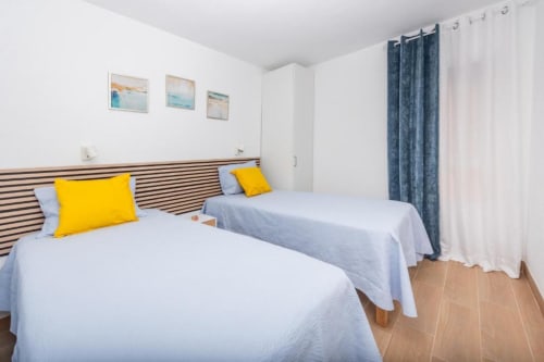 Habitación doble con cabecero a rayas, almohadas amarillas y ropa de cama azul en Smart Rent Fuerteventura