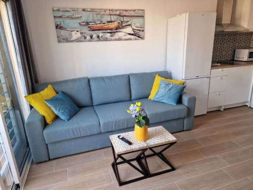 Sofá gris con cojines amarillos y azules en el área de estar moderna del apartamento en Smart Rent Fuerteventura