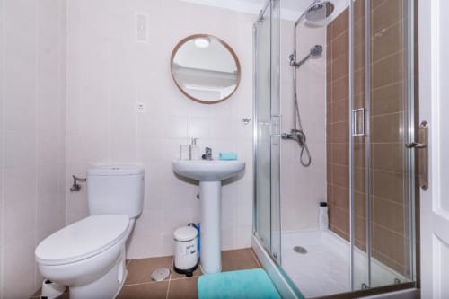 Moderno baño del apartamento Brisa del Atlántico en Smart Rent Fuerteventura con inodoro, lavamanos pedestal, espejo redondo y